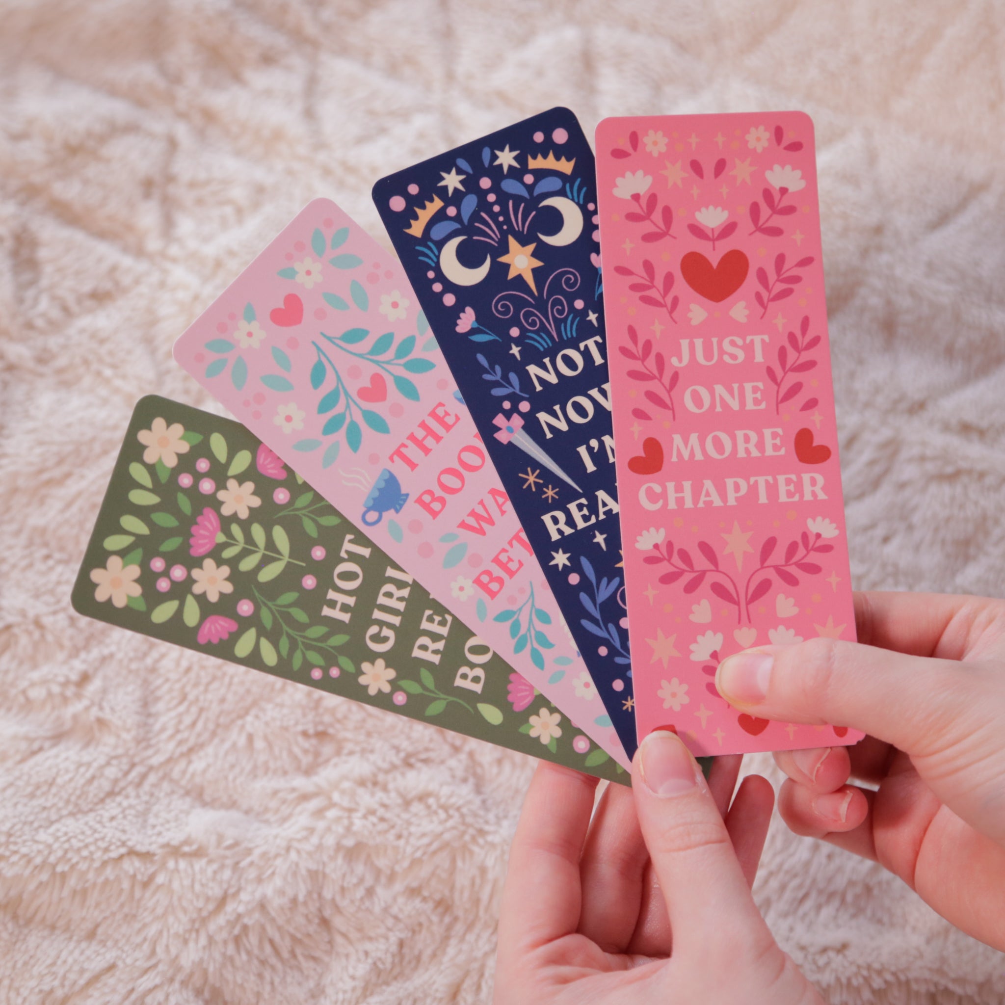 A photograph of four hand-illustrated bookmarks, each with florals and a unique quote - the perfect gift for readers and book lovers.