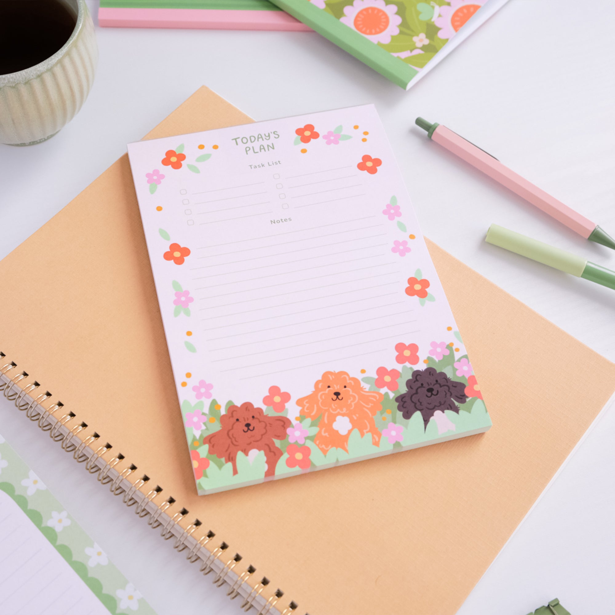Notepad with cartoon dogs and flowers on a desk with stationery items