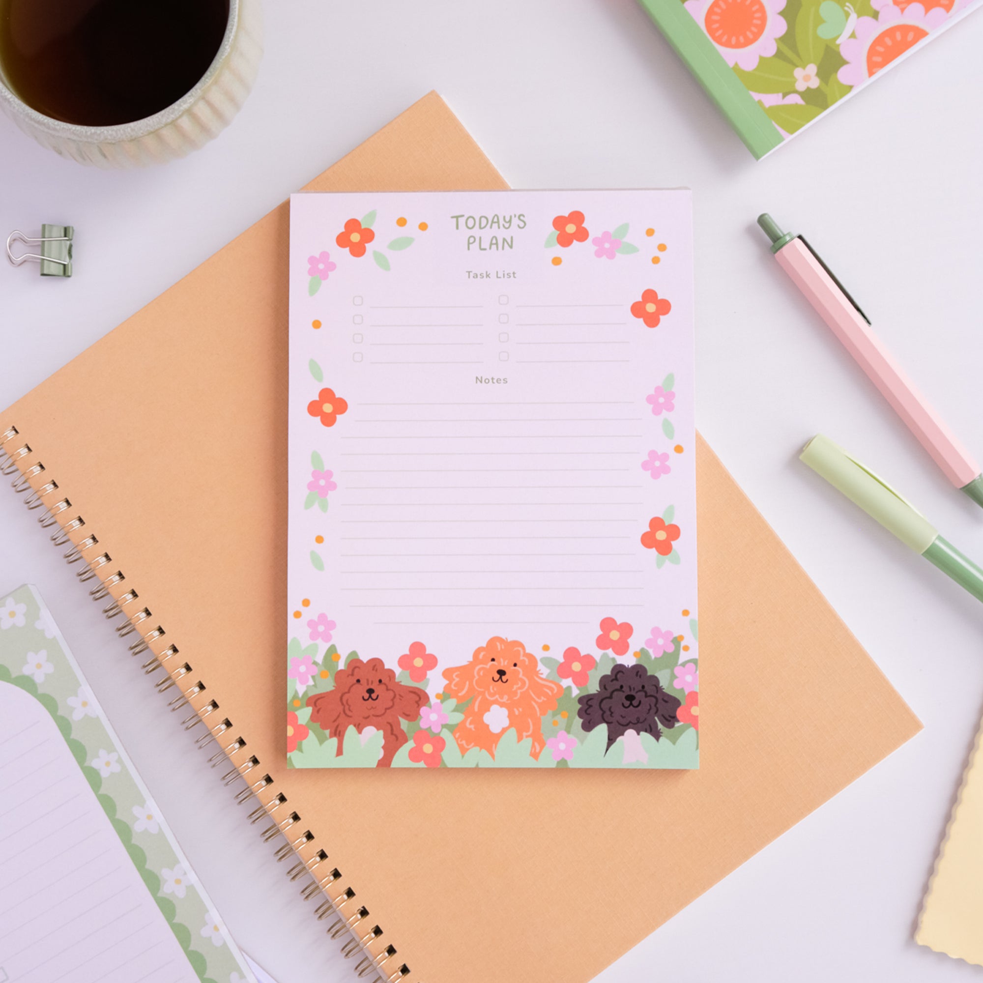 Floral planner pad with cute animal illustrations on a desk with stationery items.