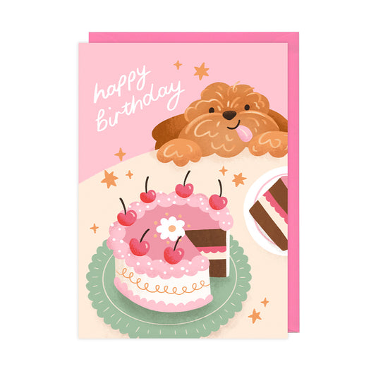 A pink birthday card featuring a cake and a fluffy dog. 