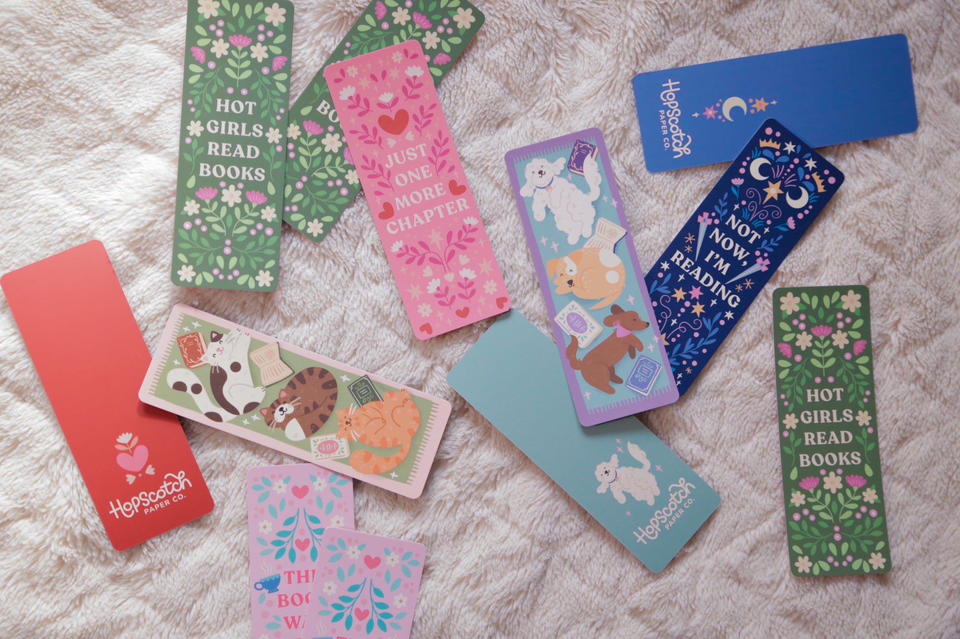 A photograph of a collection of unique, colourful and hand-illustration bookmarks against some bedding - a great gift for readers and book lovers. 