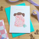 A photograph of a get well soon greetings card featuring a puppy wrapped in a blanket with a cup of tea. 
