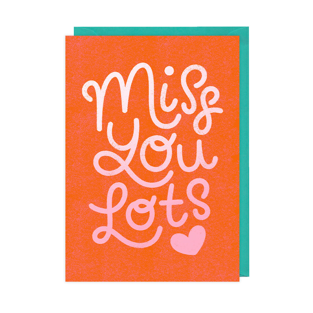 A red greetings card that reads "miss you lots" with a pink heart. 