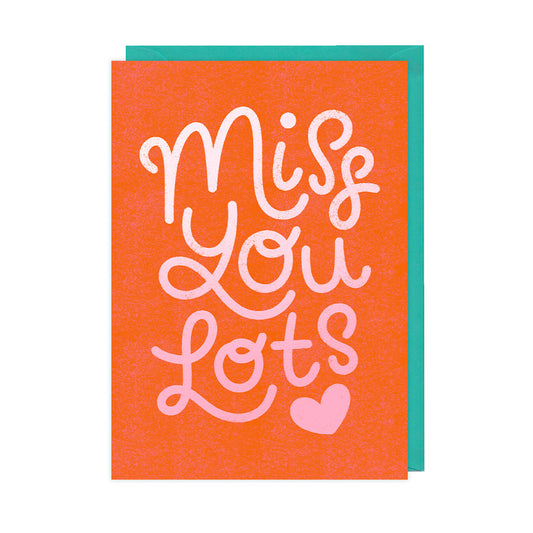 A red greetings card that reads "miss you lots" with a pink heart. 