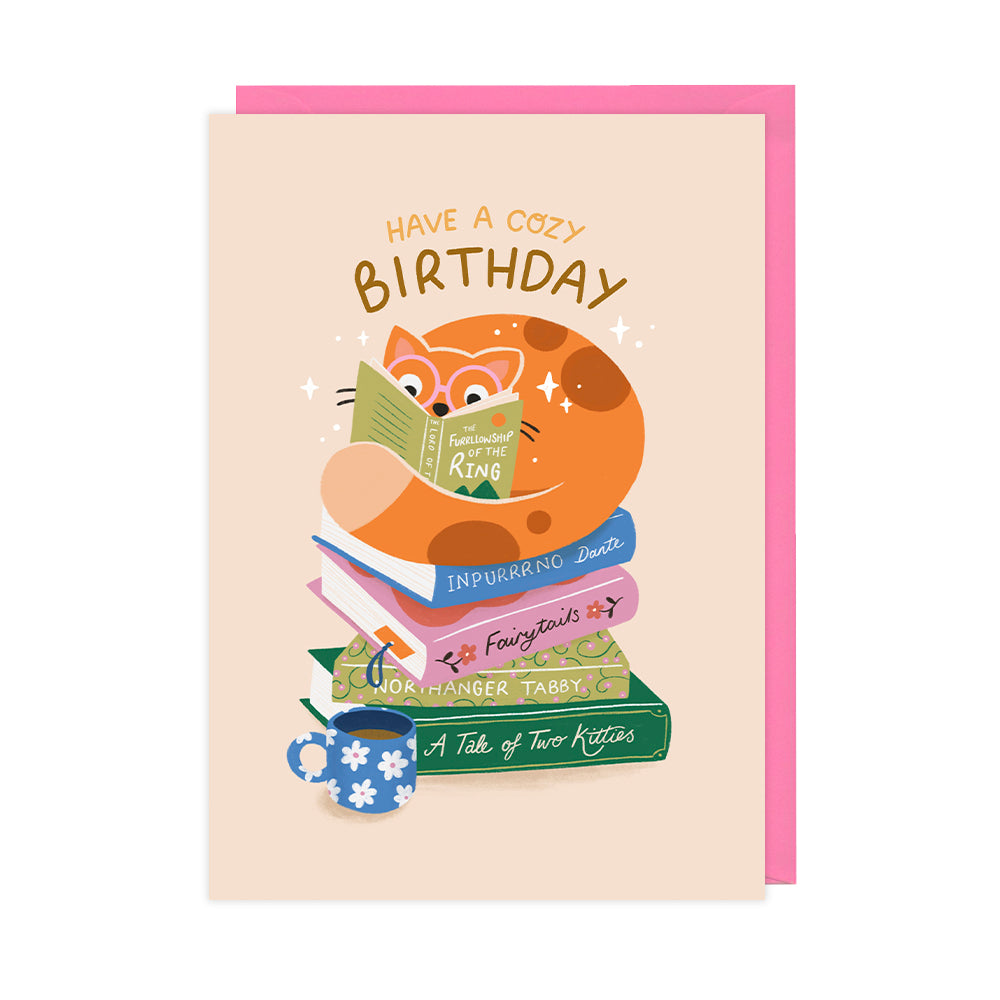 An illustrated birthday card of a ginger cat reading a stack of books. 