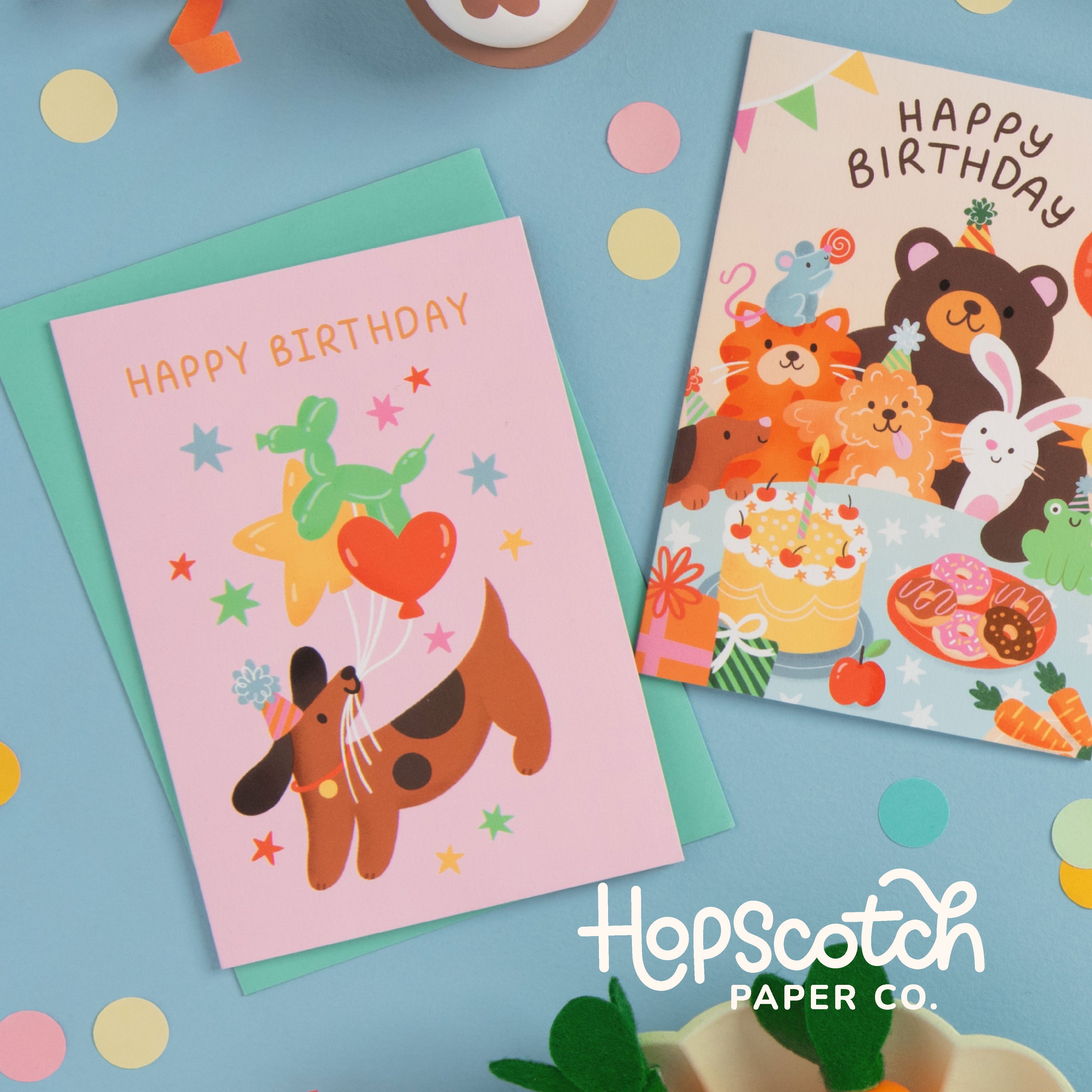 Two birthday cards with animal illustrations on a colorful background, featuring the brand 'HopScotch Paper Co.'